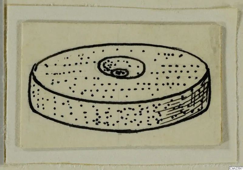 Ink drawing of a flat disc-shaped object with a central boss and rows of small dots on its top and side.