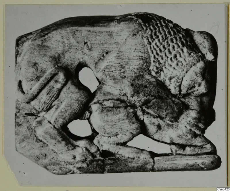 Carved relief plaque with a figure in low relief and irregular openings, photographed on a grey card