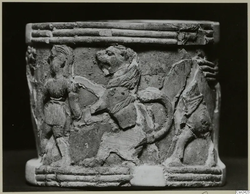 Carved cylindrical bone object with relief of a lion and a standing figure, ridged bands at top and base
