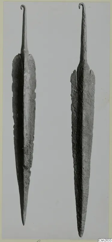 Two long metal blades with curled hooked tangs, set side by side against a plain grey background.