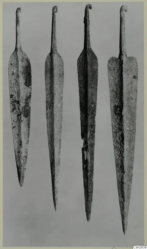 Four long metal blades with curled tangs, set side by side on a grey background