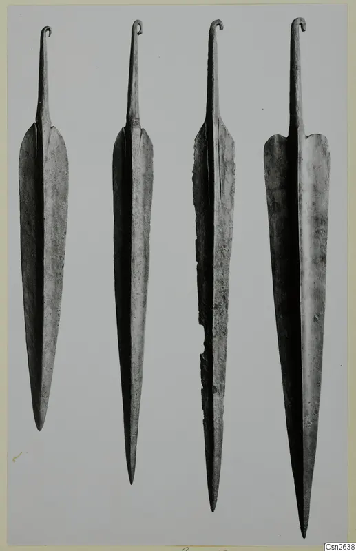 Four long metal blades with hooked tangs, laid out in a row on a grey background