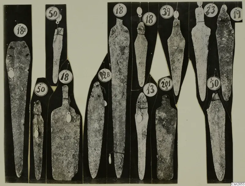 BA weapons: about fifteen grey metal blades and tanged objects, each on a black strip with a numbered tag.