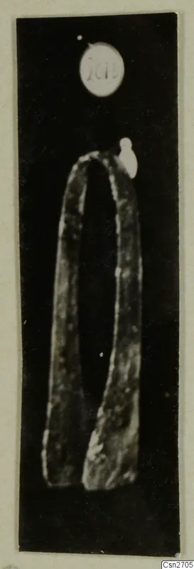 Bronze tool with two long arms joined by a rounded bend, photographed against a black background