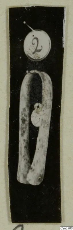 Bronze tool: a long metal bar bent into an open loop with a small disc attached, shown with a number label