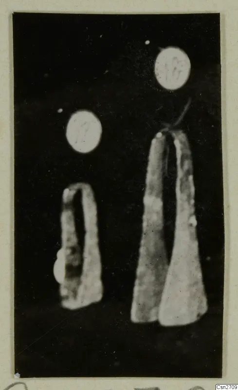 Two bronze tools photographed against a black background, each with a round number label above it.