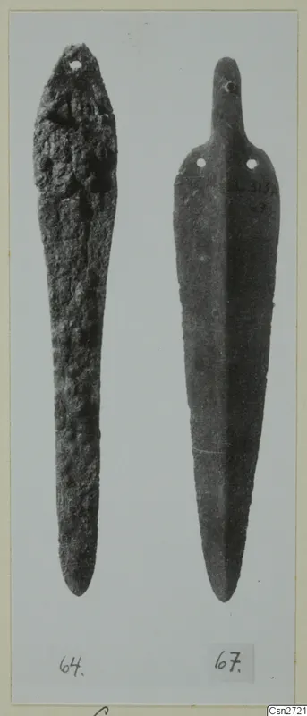 Two elongated bronze objects with perforated ends, shown side by side on a mounted card