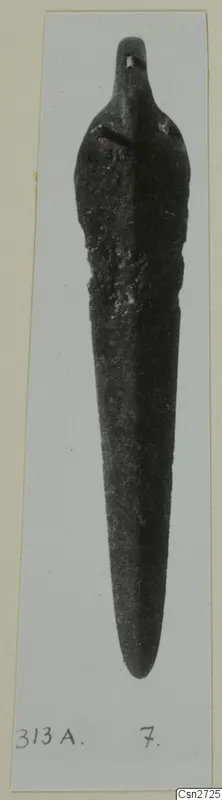 Bronze tool with a long tapering blade and a small knob at the top, photographed on a mount.