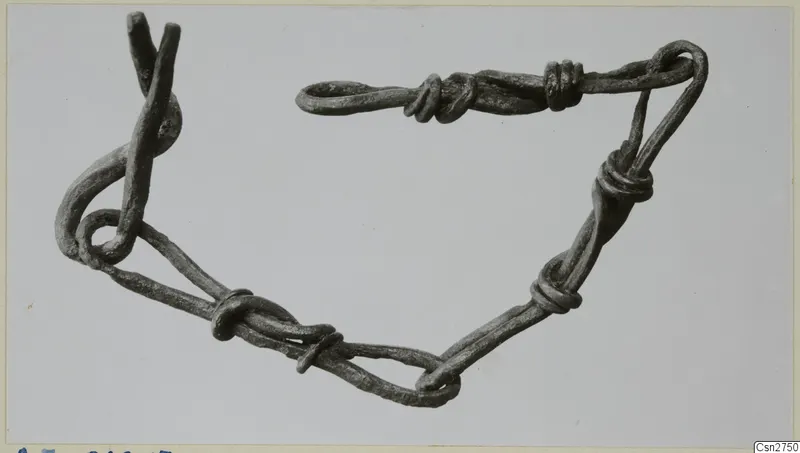 Bronze object of looped and coiled wire strands, photographed on a plain grey background