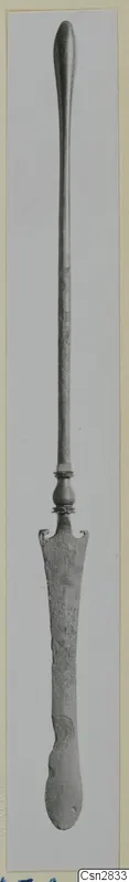 Bronze toilet implement with a long slender handle and a flat, notched blade