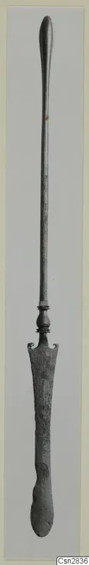Bronze toilet implement with a long slender shaft and a flat spatula-like end, shown upright