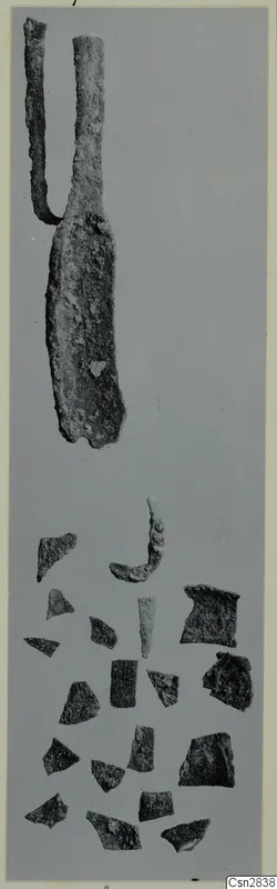 Corroded metal implement with two arms above a scatter of small fragments, bronze toilet requisites