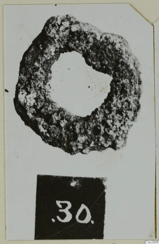Corroded bronze ring-shaped object with a large central hole, shown with a number label below it