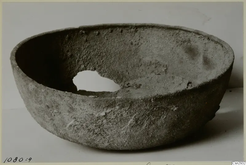 Rounded bowl with a wide open mouth and a hole broken through one side of its wall.