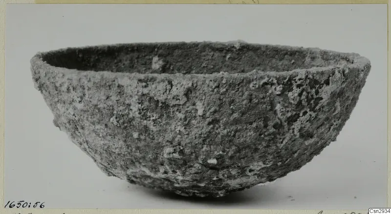 Heavily encrusted bowl with a wide mouth and rounded sides, seen from the side against a plain background.