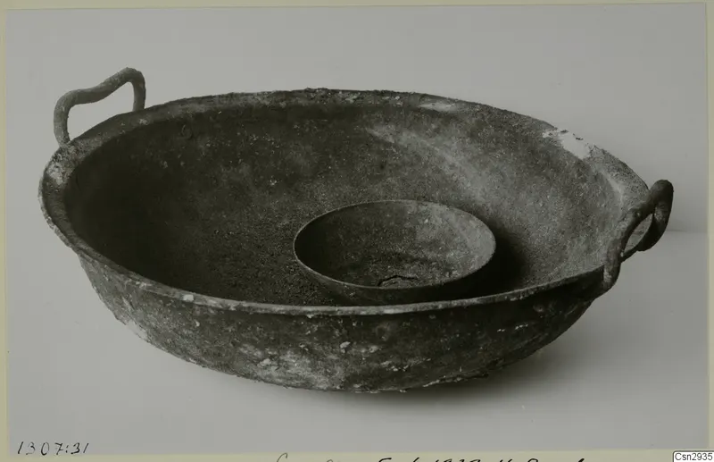 Large corroded metal bowl with two loop handles, with a small dish nested inside it