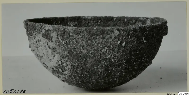 Bowl before conservation, with a rough, crusted dark surface and pale encrusted patches.