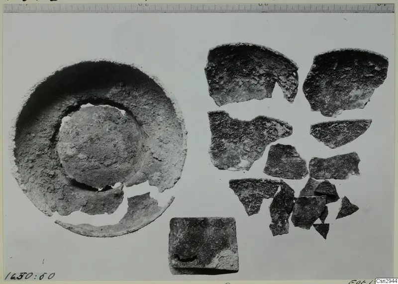 Shallow dish with broken rim beside a scatter of pottery sherds, shown before conservation