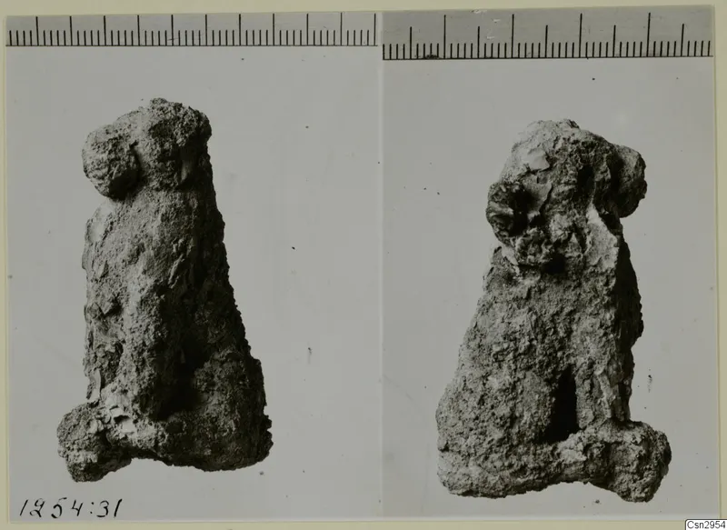 Two views of a small, heavily encrusted figure-like object, with a scale ruler along the top edge