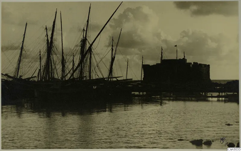 Paphos Castle silhouetted behind a row of sailing boats moored in the harbour at Paphos