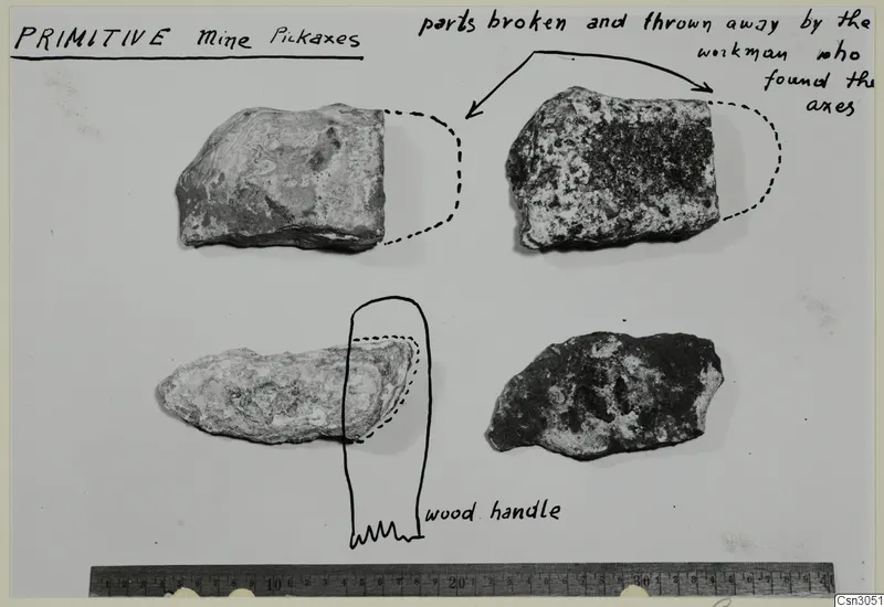 Four worked stone objects on a card with handwritten notes, dashed outlines of missing parts and a wooden handle sketch