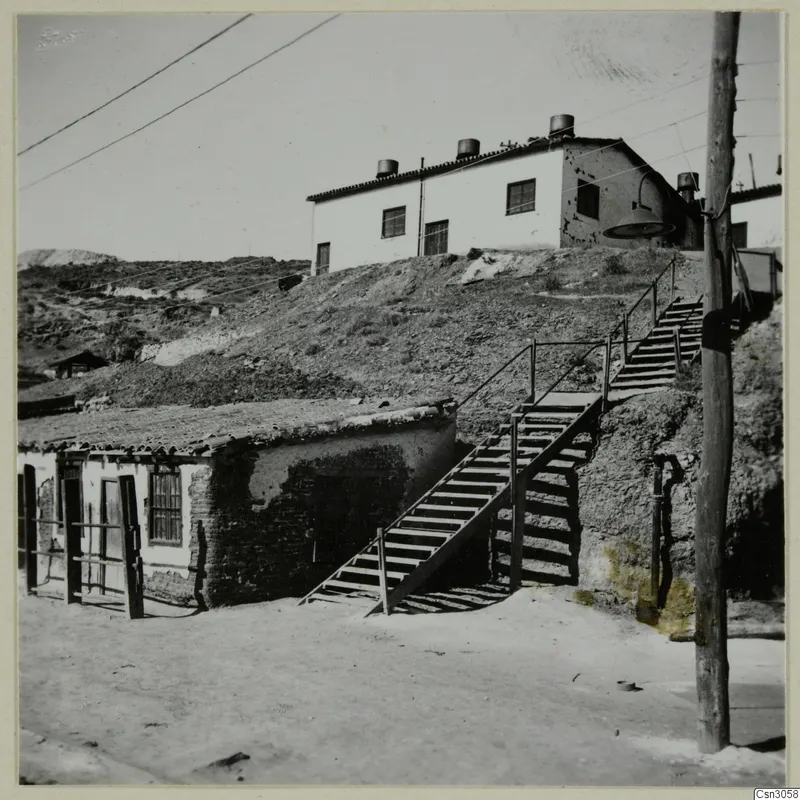 Wooden staircase climbing a hillside past low buildings at Skouriotissa