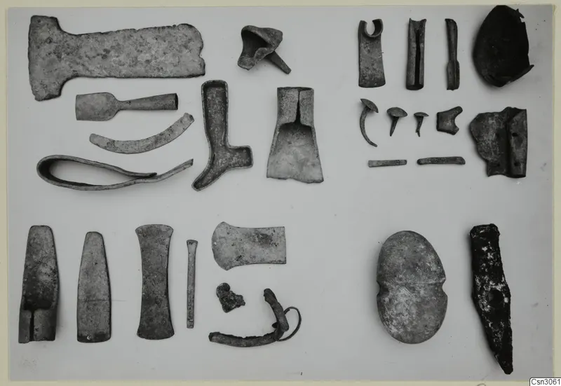 Various corroded metal tools and fragments from Mathiati laid out in rows on a pale surface