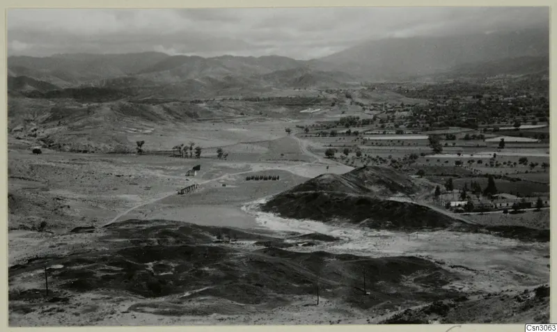 View over Skouriotissa from Foukassa Hill, with dark slag heaps in the foreground and a valley and mountains beyond
