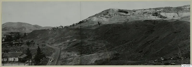 Dark slag heap on the slope of Foukassa Hill at Skouriotissa, with a winding road and small figures below
