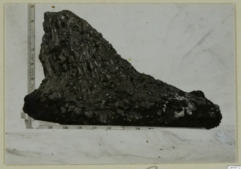 Dark, knobbly lump of material photographed beside a measuring ruler, from the copper mining series
