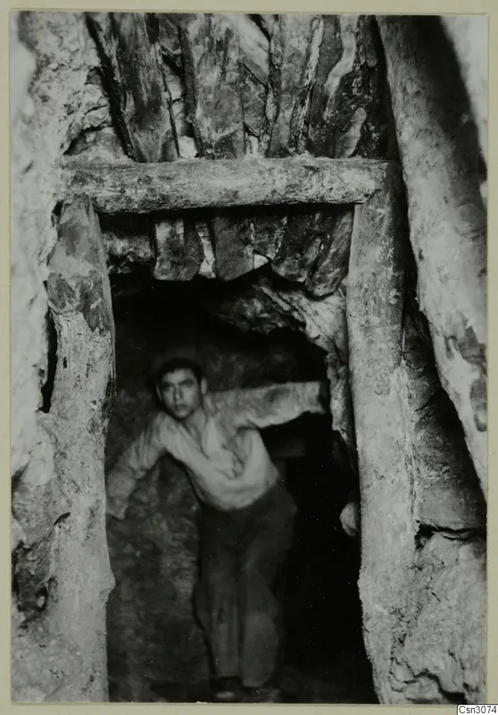 Underground passage at Mavrovouni with timber beam and posts, and a young man standing in the opening