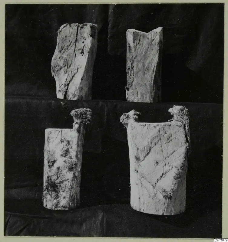 Four upper ends of ancient wooden parts, photographed against a black cloth backdrop