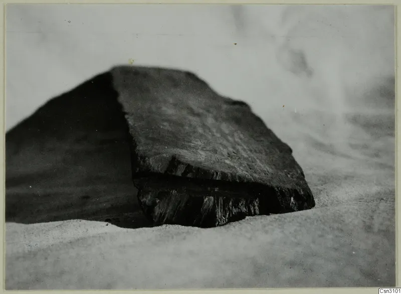 Dark wooden block with a split, broken end, resting on a pale cloth