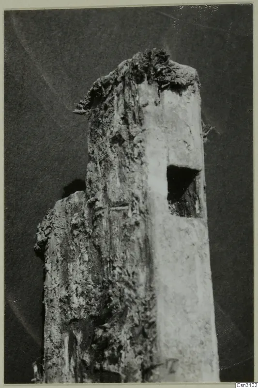 Weathered wooden timber with a rectangular hole cut into its side, and a second piece of wood behind it