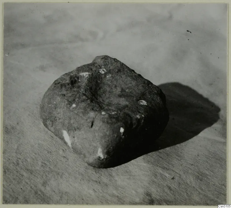 Rounded stone with white flecks, photographed on a plain surface; probably used as a base for a timber post.