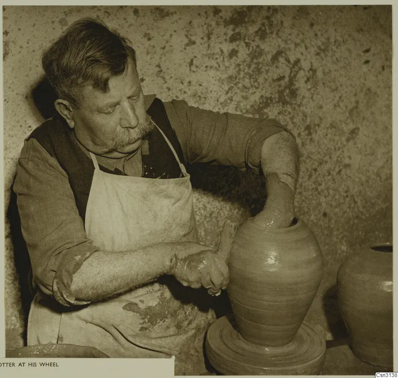 A potter shaping a tall clay vessel on his wheel
