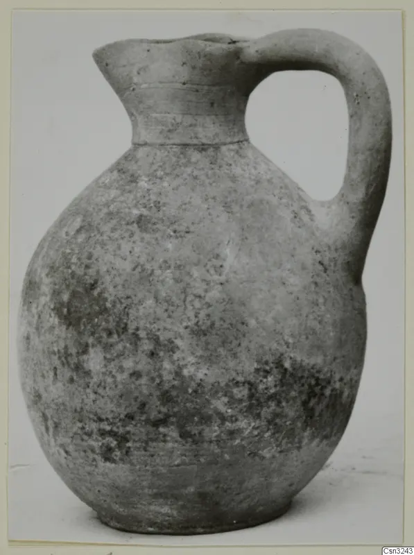 Pottery jug with a single loop handle and a flared neck, photographed against a plain background.