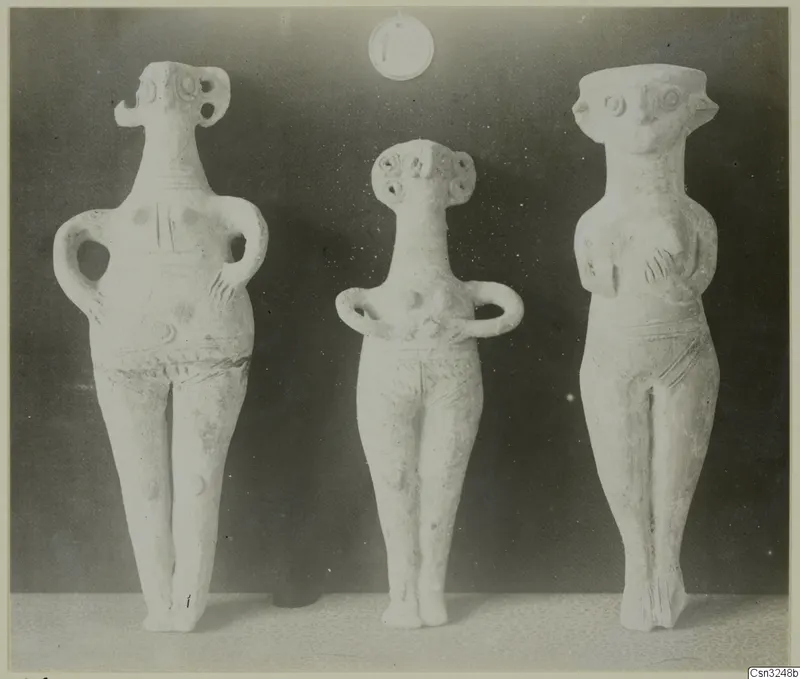 Three pale clay figurines standing side by side, from Katydhata