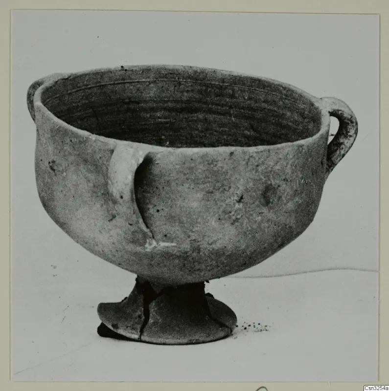 Plain white pottery bowl with two handles on a pedestal foot, photographed against a plain background.