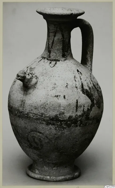 White Painted jug with a single strap handle, a knob on one side and dark painted bands, on a grey background