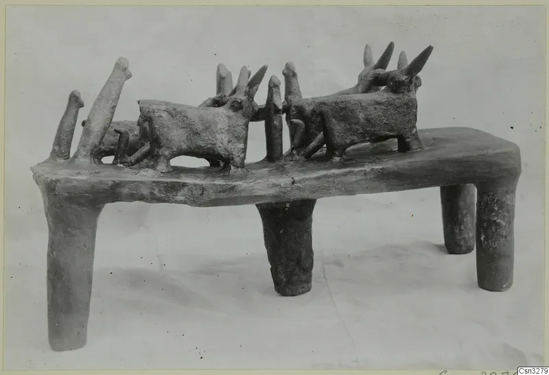 Terracotta model of a rectangular stand on four legs, with several horned animal figures and upright posts on its top