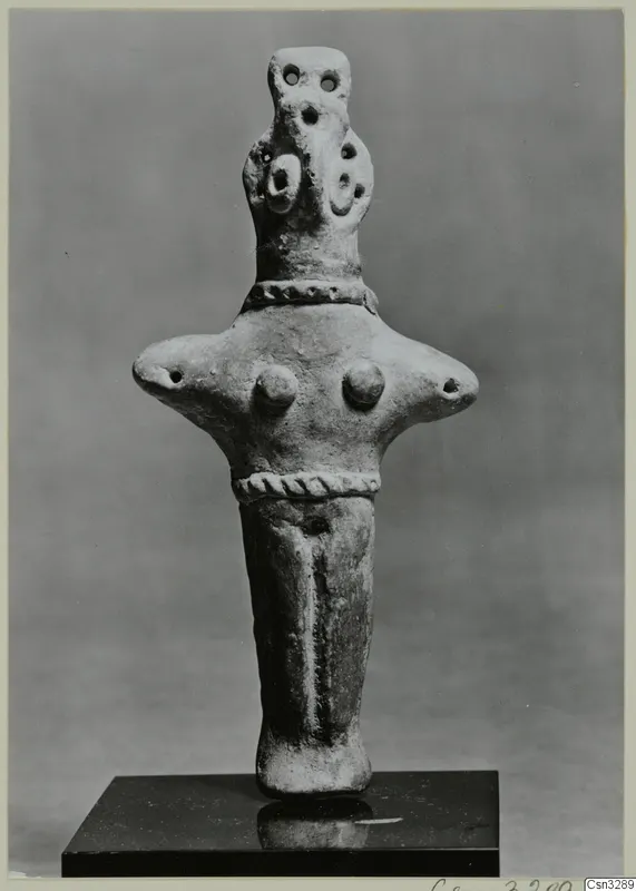 Clay figurine with a bird-like head and twisted rope bands, standing on a dark stand