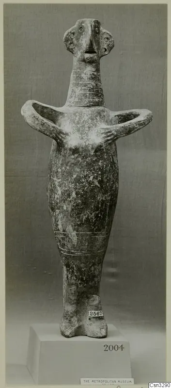 Figurine with arms bent outward and hands at the chest, photographed on a plinth against a grey backdrop