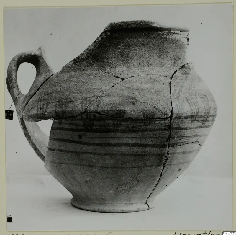 Painted pottery vessel from Milia with a single loop handle, dark horizontal bands and a broken rim