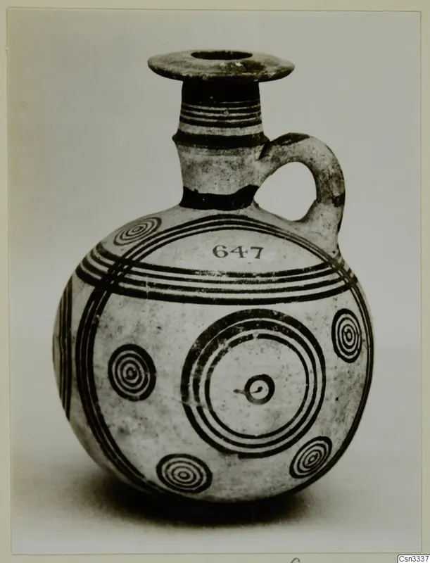 Round pottery juglet with a flared rim, one handle and dark concentric circles and bands painted on a pale body.