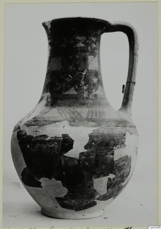 Jug with a single loop handle and dark painted bands and geometric patterns, shown against a plain background