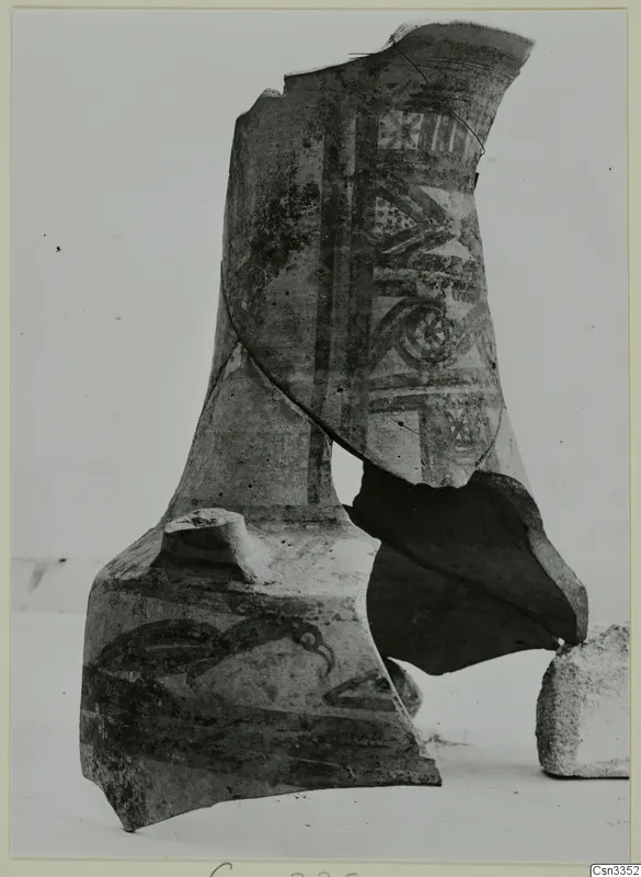 Painted pottery sherds with vertical bands, geometric panels and a curved motif, propped together on a pale surface