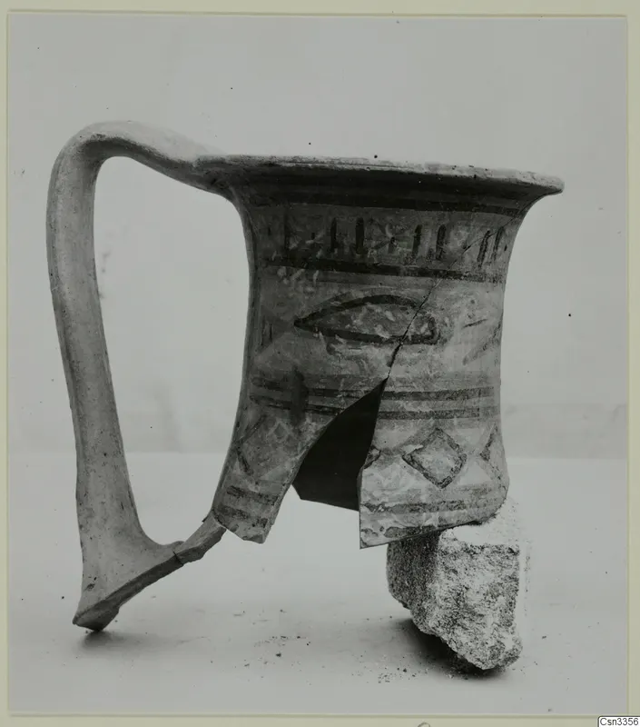 Painted pottery jug with a tall loop handle, decorated with dark bands, a fish-like motif and a lozenge.