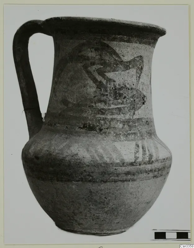 Wheel-made jug with a high loop handle and dark painted bands and motif on a pale body.