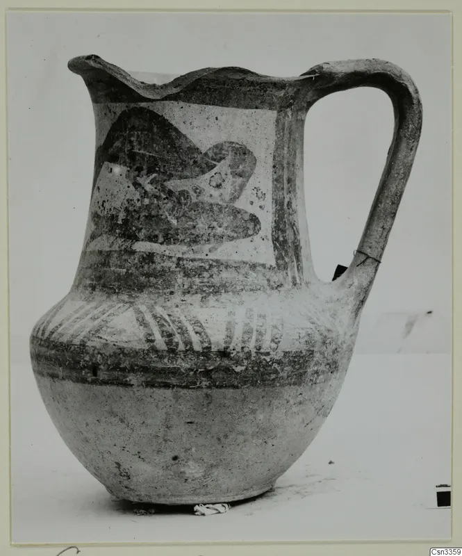 Bichrome painted jug with a wavy rim, strap handle and a dark motif on the shoulder panel